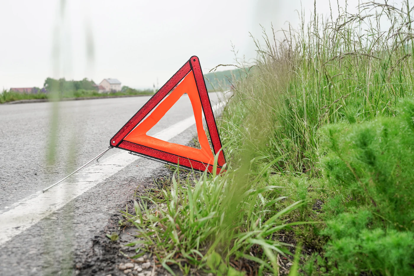 Yol kenarına konmuş kırmızı reflektör üçgeni, arkasında boş asfalt yol